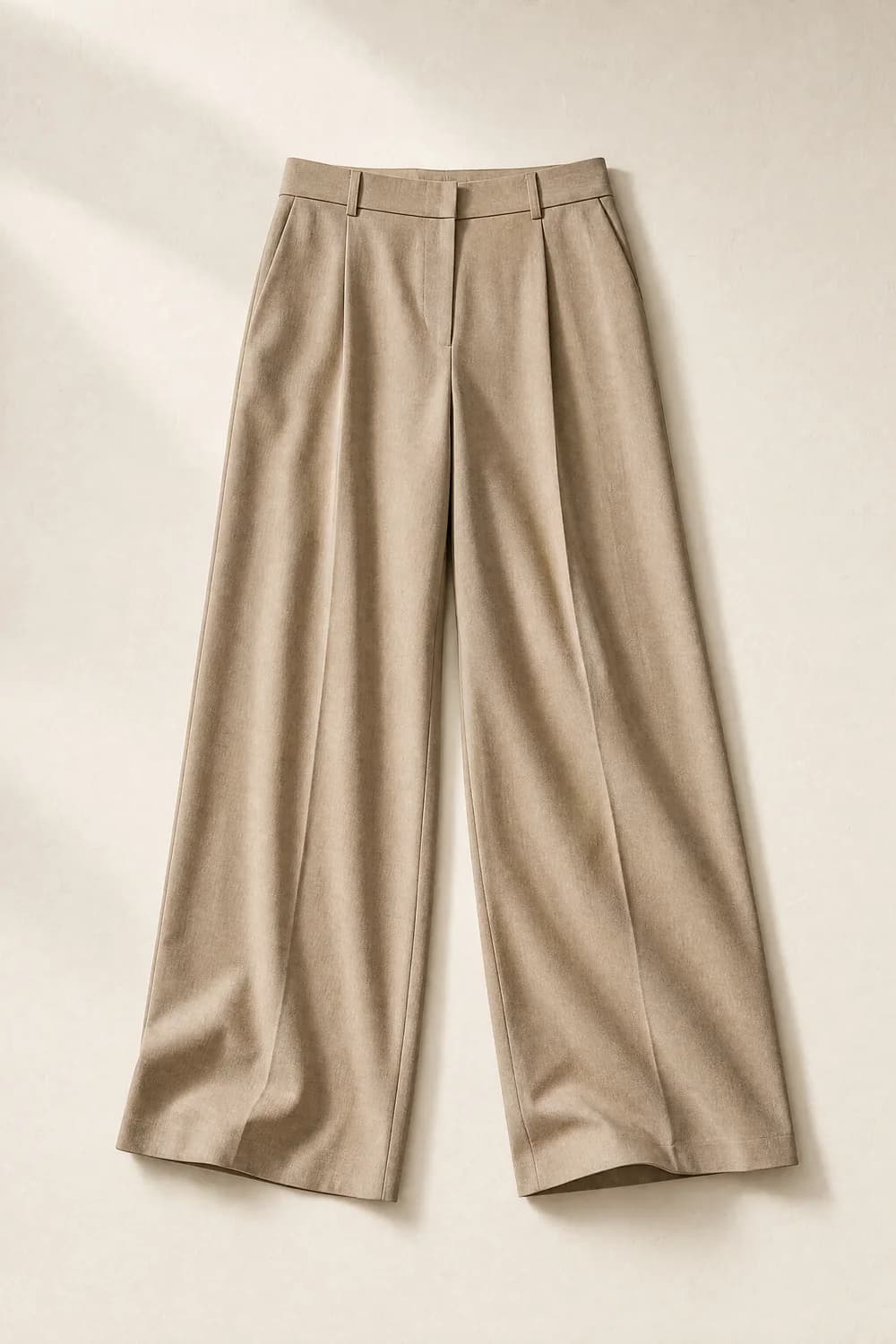 Wide-leg trousers, laid flat on a warm paper surface and photographed from above